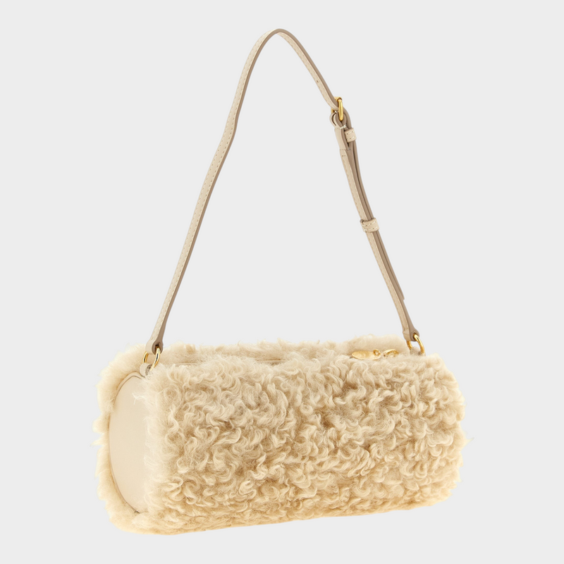 Esmire & Co beige cylindrical clutch bag in faux sheepskin polyester with an adjustable strap and gold hardware.