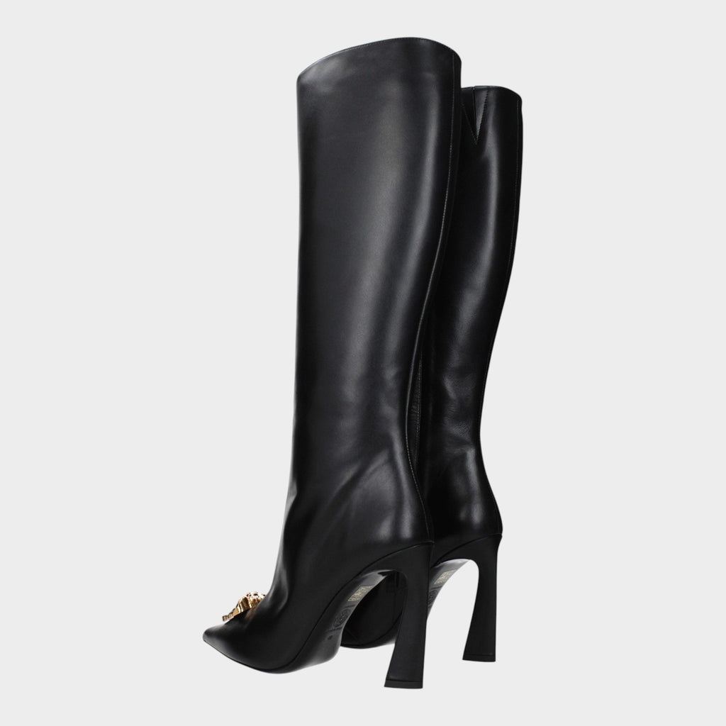 Esmire & Co black leather high heel boots with gold front detail and pointed toe, shown from a side angle.