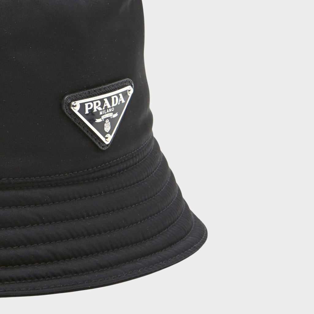 Esmire & Co black nylon bucket hat featuring the iconic Prada triangle logo on a quilted brim detail.