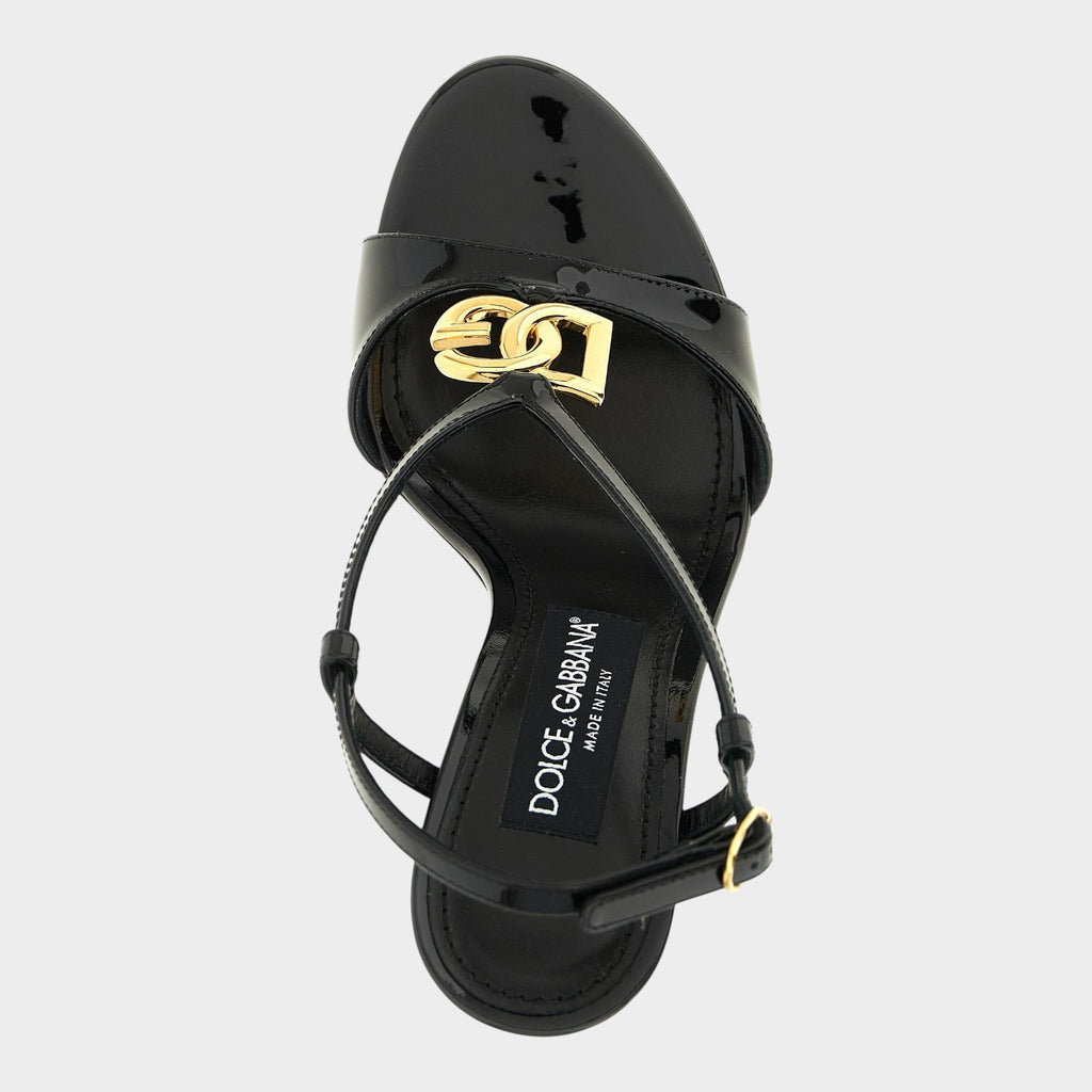 Esmire & Co black patent calfskin stiletto sandals featuring a gold DG logo and adjustable ankle strap.
