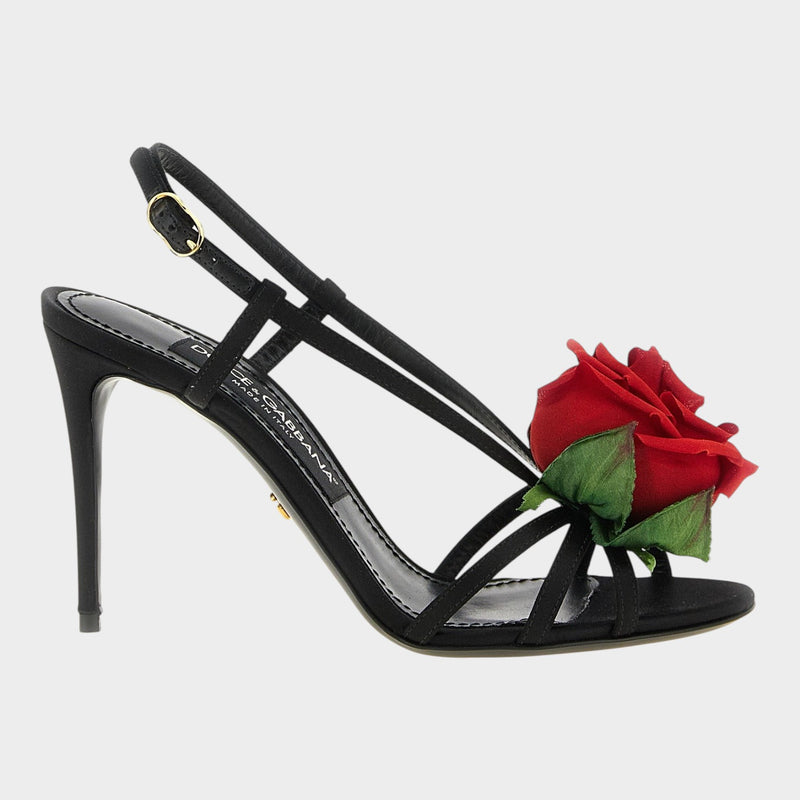 Esmire & Co black satin stiletto sandals featuring a large red rose embellishment and gold-tone slingback buckle.
