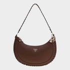 Esmire & Co brown GUESS Lucci shoulder bag with a crescent shape, braided edge detailing, and metal triangle logo.