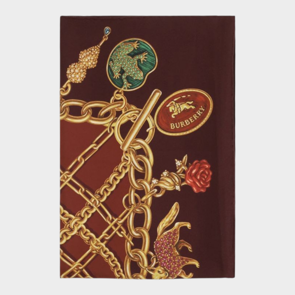 Esmire & Co Burberry bordeaux silk scarf featuring a vibrant gold charm jewellery print on a deep red background.