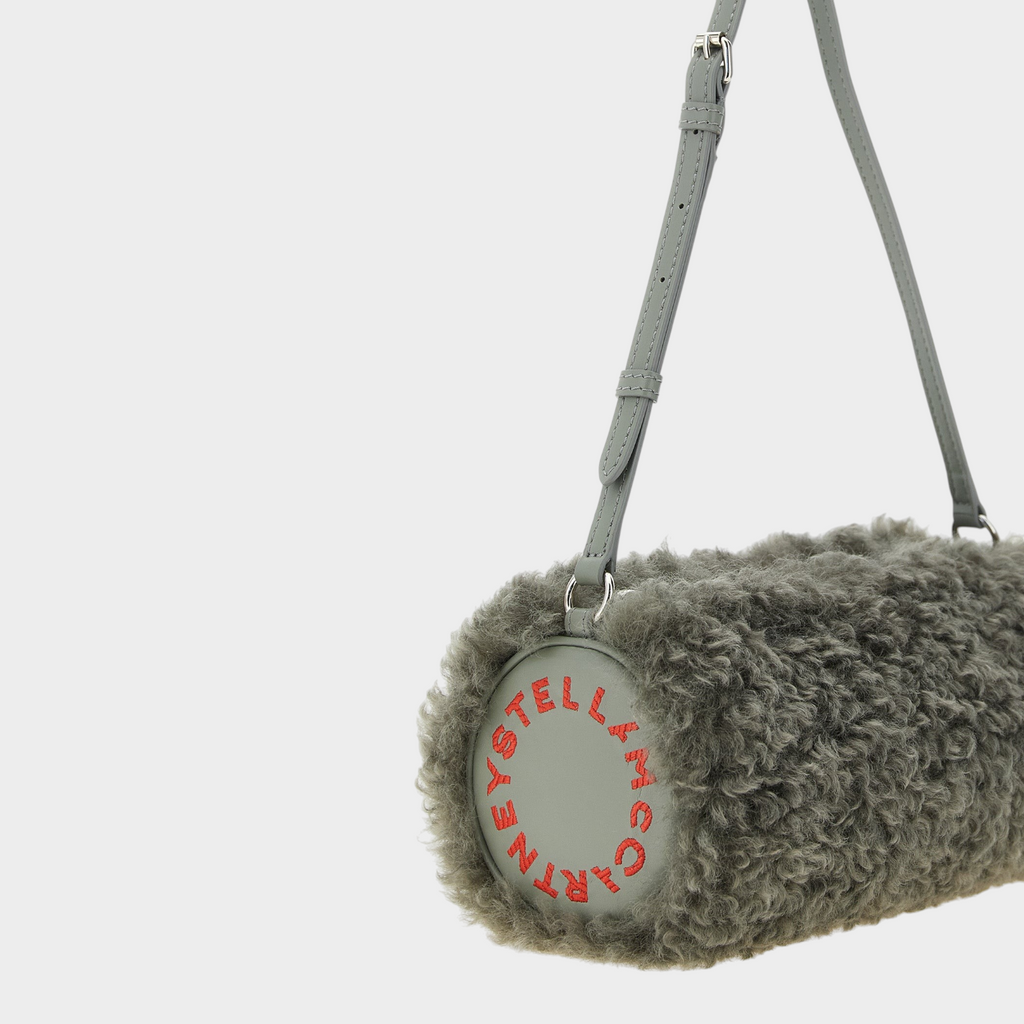 Esmire & Co gray polyester teddy clutch bag with a cylindrical shape, adjustable strap, and red circular logo detail.