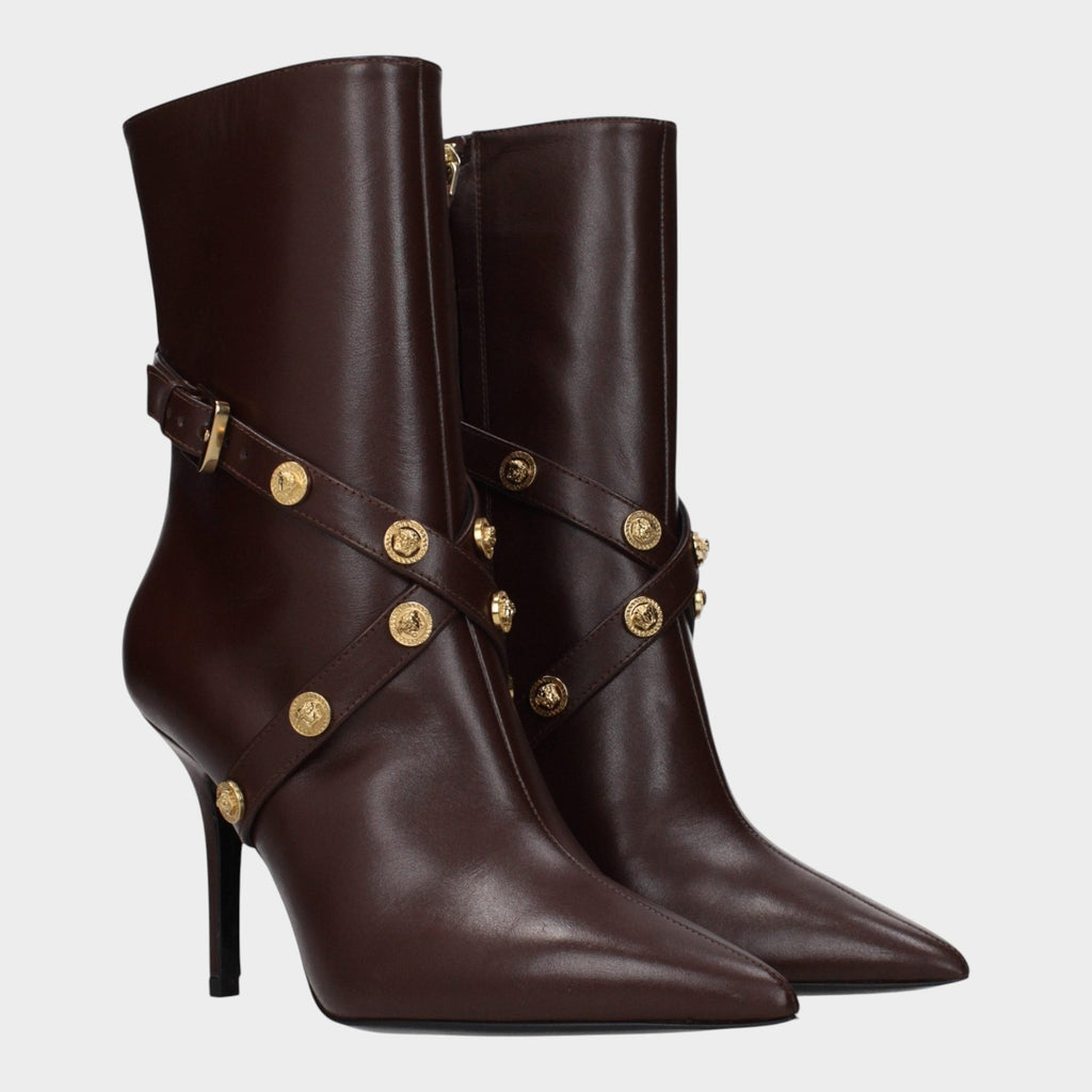 Esmire & Co Versace chocolate brown leather ankle boots with pointed toe, sculpted heel, and gold Medusa stud straps.