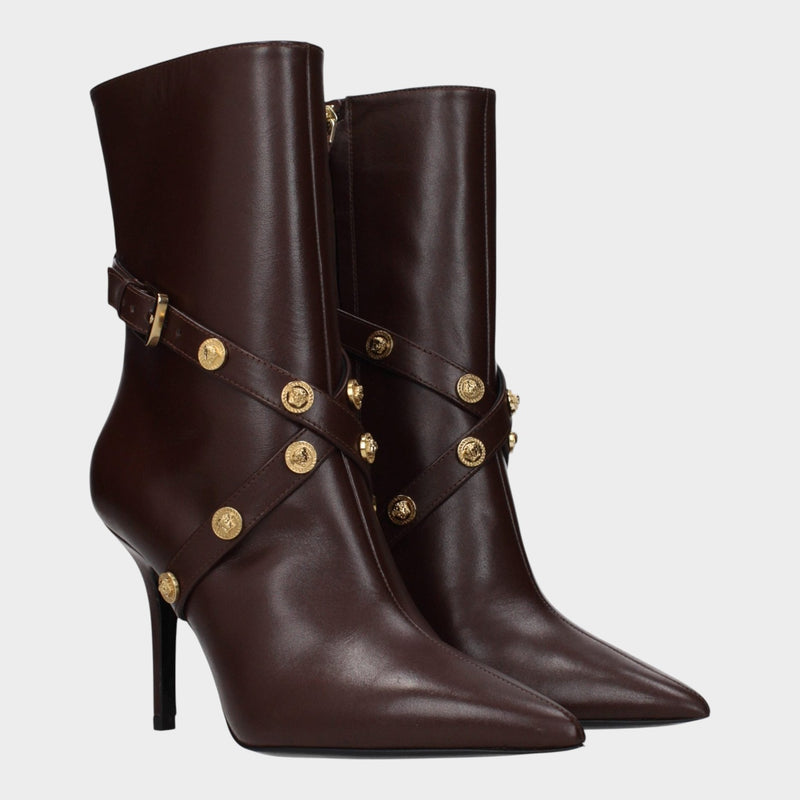Esmire & Co Versace chocolate brown leather ankle boots with pointed toe, sculpted heel, and gold Medusa stud straps.